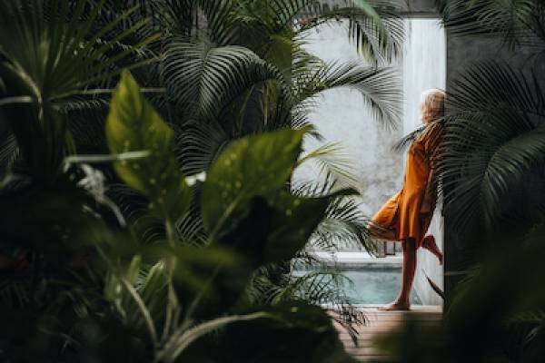 woman leaning in doorway of a dark room full of plants