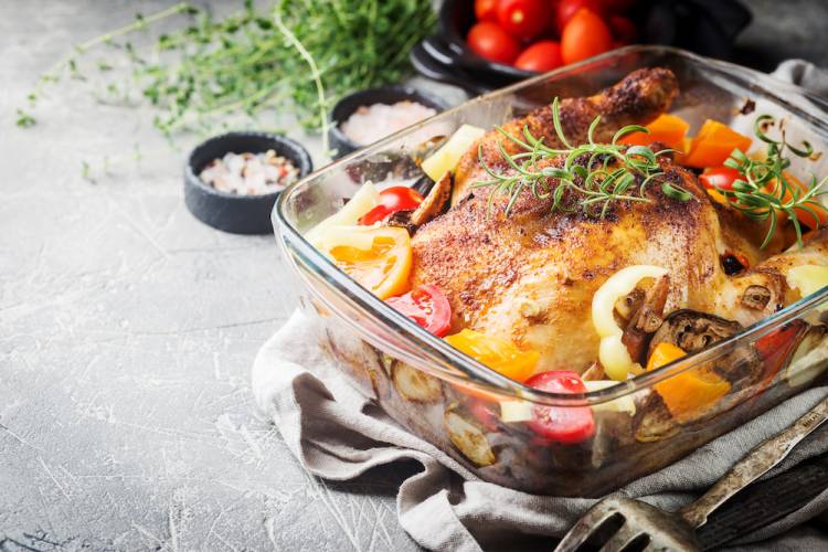 turkey in a roasting pan with rosemary on top of it